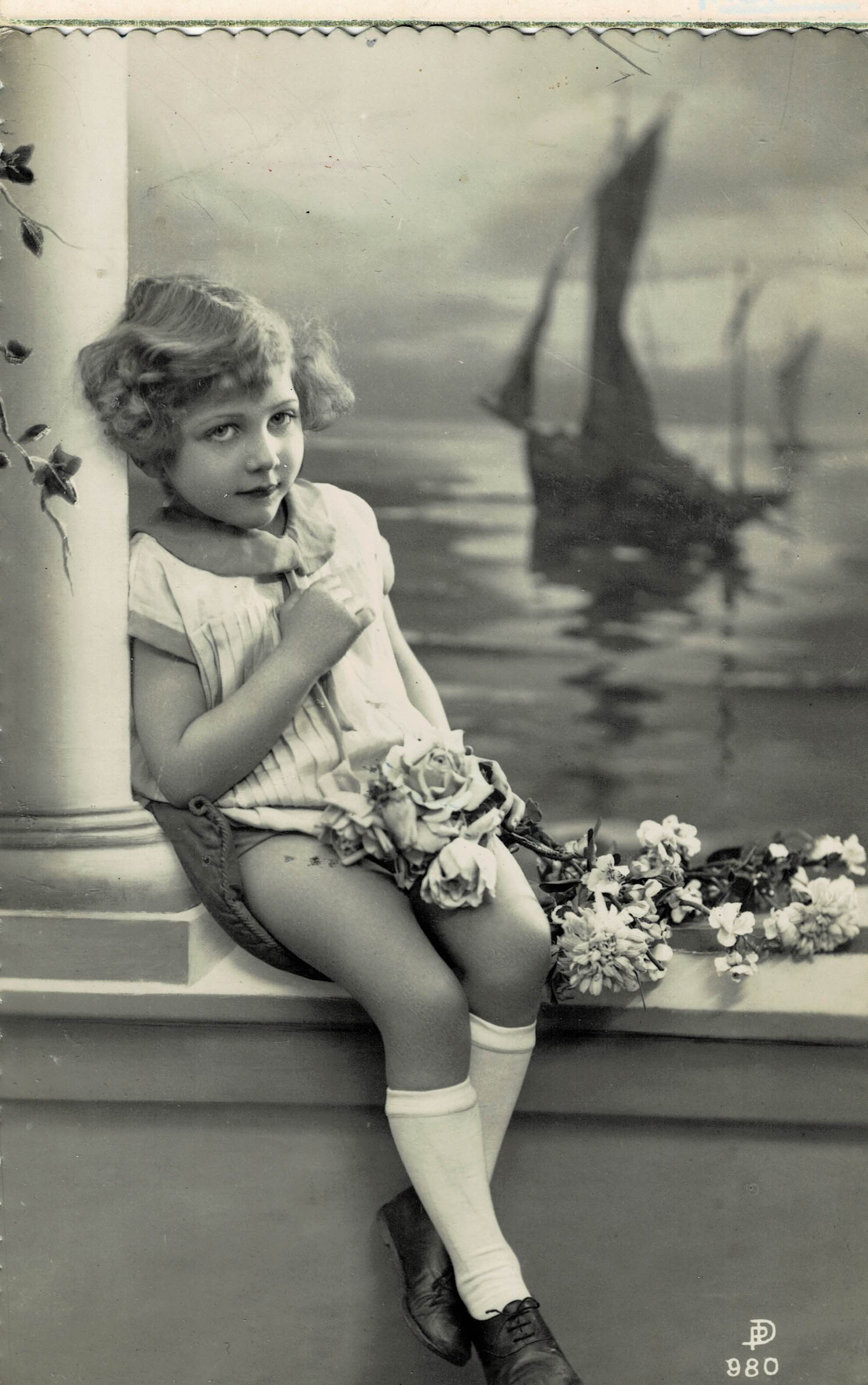 POSTAL NIÑA EN UN BALCÓN CON FLORES.